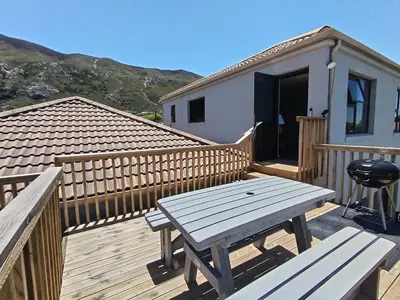 a wooden deck with a picnic table and a house at 45 on Luke in Hermanus