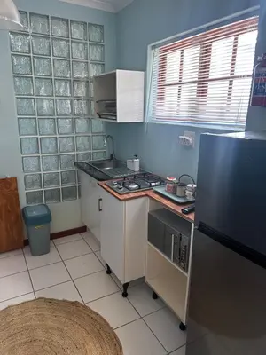a small kitchen with a stove and a refrigerator at Casa on Alamein in Cape Town