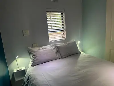 a white bed in a bedroom with a window at Casa on Alamein in Cape Town