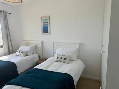 two beds in a room with white walls at BEACHFRONT Breeze in Cape Town