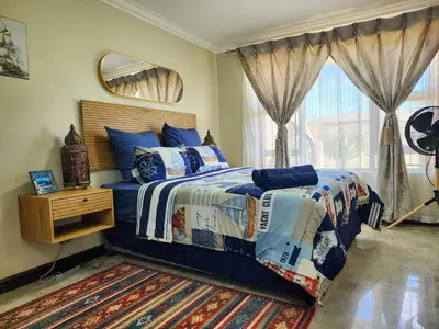 a bedroom with a bed with a blue comforter and a window at The Seagull in Cape Town