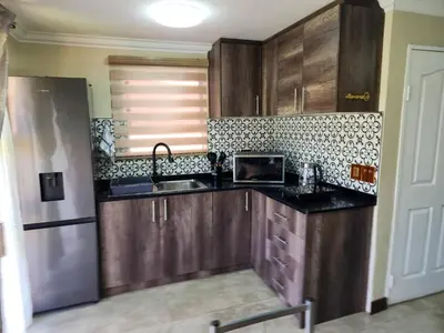 a kitchen with wooden cabinets and a stainless steel refrigerator at The Seagull in Cape Town