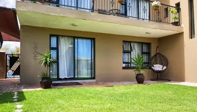 a house with two potted plants in a yard at The Seagull in Cape Town