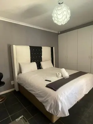 a bedroom with a large white bed with a chandelier at Zoe & Saint in Cape Town