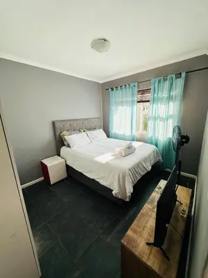 a bedroom with a large bed with blue curtains at Zoe & Saint in Cape Town