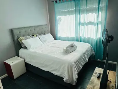 a bedroom with a white bed with a fan on it at Zoe & Saint in Cape Town