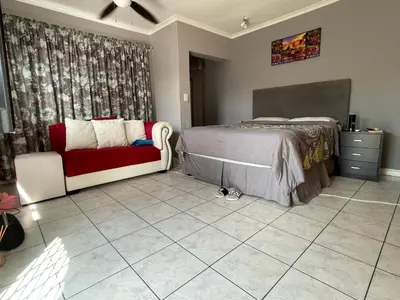 a bedroom with a bed and a red couch at Zoe & Saint in Cape Town