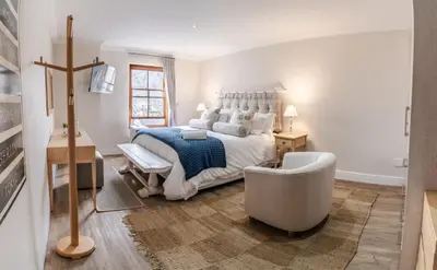 a bedroom with a large bed and a chair at Village Artisan Franschhoek in Franschhoek