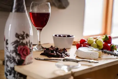 a table with a glass of wine and some food at Village Artisan Franschhoek in Franschhoek