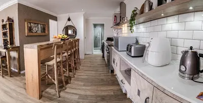a kitchen with a counter and some chairs in it at Village Artisan Franschhoek in Franschhoek