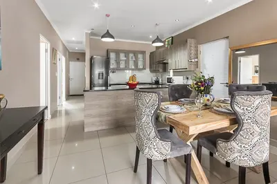 a kitchen with a wooden table and chairs at The Greenfields Suite in Cape Town