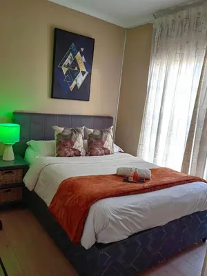 a bedroom with a large bed with a red blanket at The Greenfields Suite in Cape Town