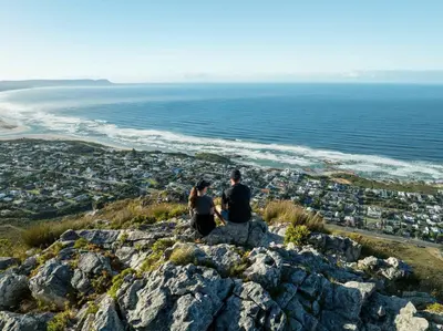 a couple sitting on a rock overlooking the ocean at Birkenhead House in Hermanus
