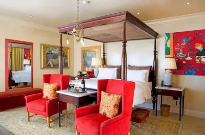 a bedroom with a canopy bed and red chairs at Birkenhead House in Hermanus