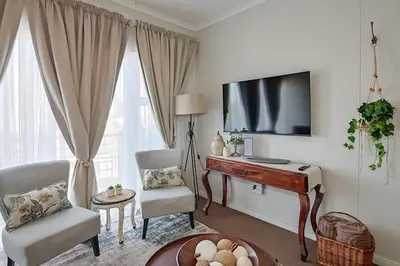 a living room with a tv and a desk and chairs at Unwind at Coral 2BR Bloubergstrand Beach Apt Walk to Beach in Bloubergstrand