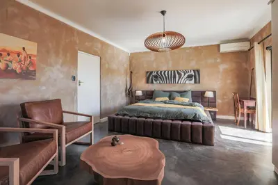 a bedroom with a bed and a chair and a table at YEBO Boutique Guesthouse in Somerset West