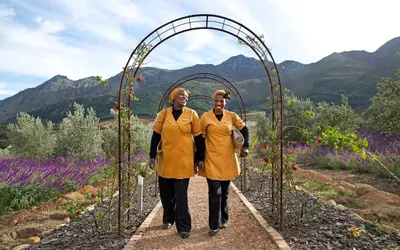 two people walking through an arch in a garden at La Residence in Franschhoek