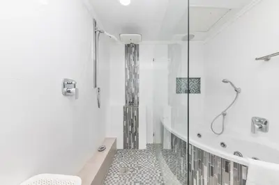 a white bathroom with a tub and a shower at Horizon Bay 202 Beachfront APT, Bloubergstrand in Cape Town
