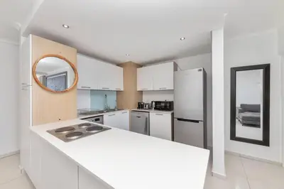 a kitchen with a white counter and a refrigerator at Horizon Bay 202 Beachfront APT, Bloubergstrand in Cape Town