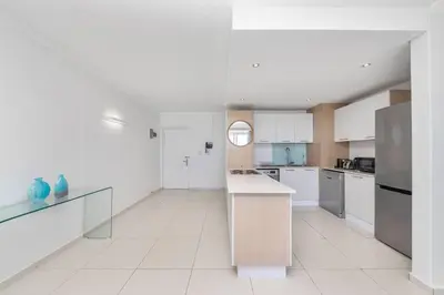 a large kitchen with white cabinets and a counter at Horizon Bay 202 Beachfront APT, Bloubergstrand in Cape Town