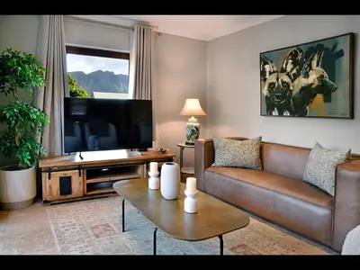 a living room with a couch and a flat screen tv at Sorbonne 6 in Franschhoek