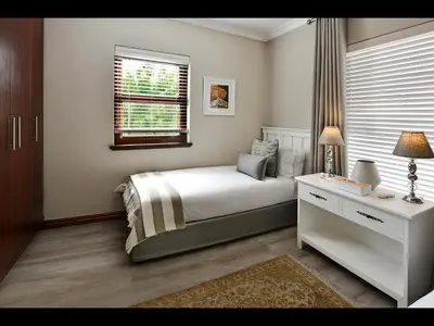 a bedroom with a bed and a desk and a window at Sorbonne 6 in Franschhoek