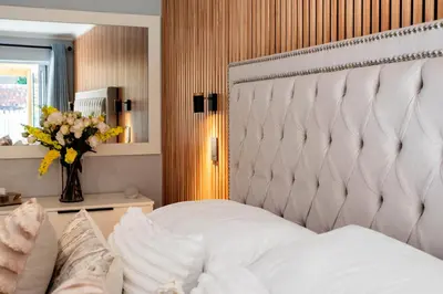 a bedroom with a white bed and a vase of flowers at Von Chambers Blouberg in Cape Town