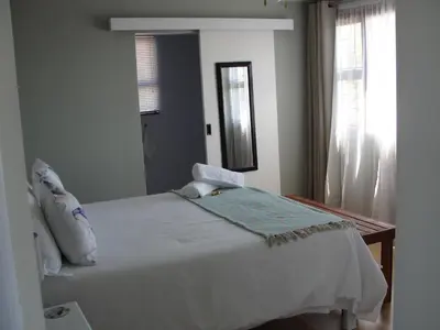 a bedroom with a white bed and a mirror at 113 Reasons Self Catering in Cape Town