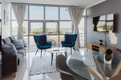 a living room with a couch and chairs and a table at St Tropez Beachfront 108 in Cape Town