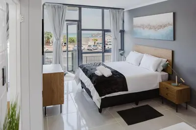 a bedroom with a bed and a large window at St Tropez Beachfront 108 in Cape Town