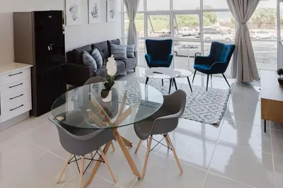 a living room with a glass table and chairs at St Tropez Beachfront 108 in Cape Town