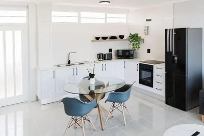 a kitchen with a glass table and blue chairs at St Tropez Beachfront 108 in Cape Town