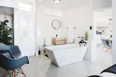 a white bathroom with a white tub and a chair at St Tropez Beachfront 108 in Cape Town