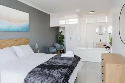 a bedroom with a bed and a tub and a sink at St Tropez Beachfront 108 in Cape Town