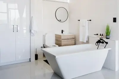 a white bathroom with a tub and a toilet at St Tropez Beachfront 108 in Cape Town