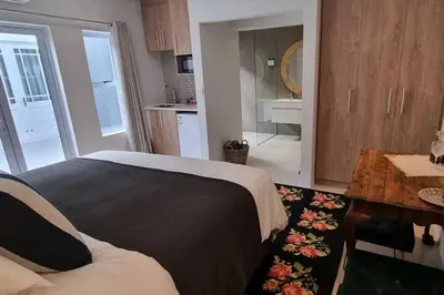 a bedroom with a bed and a table and a kitchen at C'est la Vie 6 Standard Apartment in Franschhoek