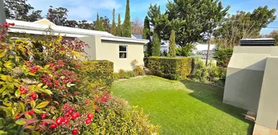 a garden with green grass and flowers and a house at C'est la Vie 6 Standard Apartment in Franschhoek