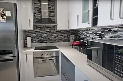 a kitchen with white cabinets and a stainless steel refrigerator at Dolphin Beach Estate 131sm in Cape Town