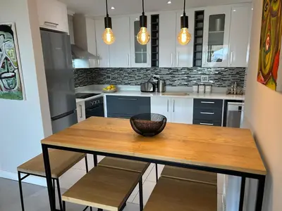 a kitchen with a wooden table with chairs and lights at Dolphin Beach Estate 131sm in Cape Town
