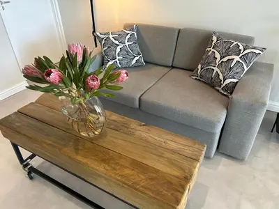a living room with a couch and a vase of flowers on a table at Dolphin Beach Estate 131sm in Cape Town