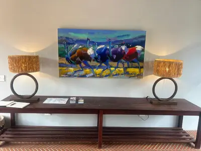 a table with two lamps and a painting on the wall at Zeven Eike Homestead in Stellenbosch