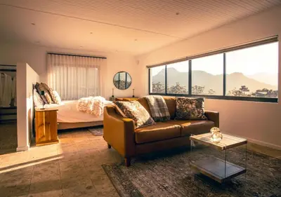 a living room with a couch and a bed at Wildeberg Dam House Cottage in Franschhoek