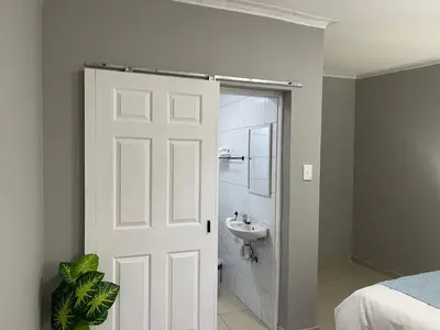 a white door leading to a bathroom with a sink at Maita Guest in Cape Town