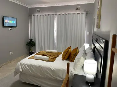 a bedroom with a large bed with white sheets and pillows at Maita Guest in Cape Town
