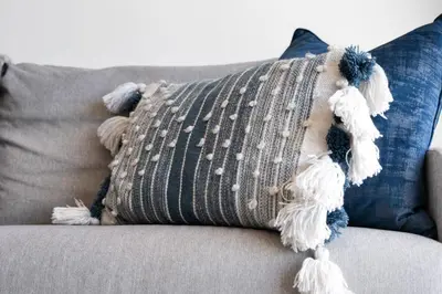 a pillow on a couch with tassels on it at The Bay A602 in Cape Town
