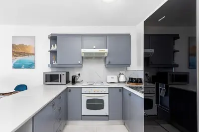 a white kitchen with blue cabinets and appliances at The Bay A602 in Cape Town