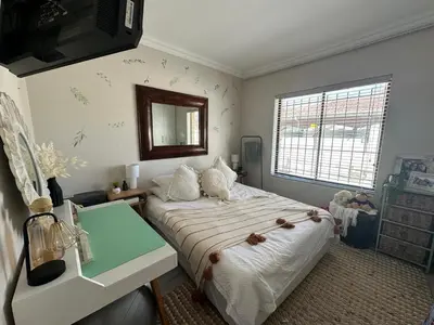 a bedroom with a large bed and a mirror at Strand Holiday home in Cape Town