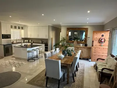 a kitchen and living room with a wooden table and chairs at Strand Holiday home in Cape Town