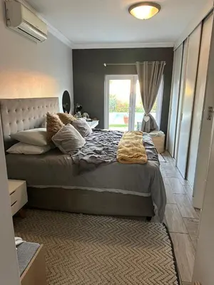 a bedroom with a large bed and a window at Strand Holiday home in Cape Town