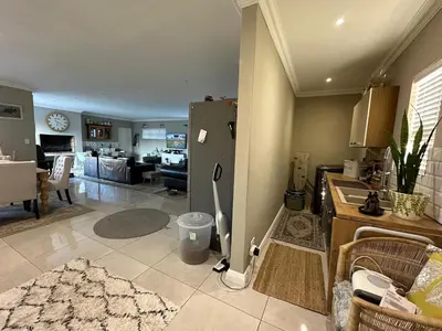 a kitchen with a refrigerator and a living room at Strand Holiday home in Cape Town